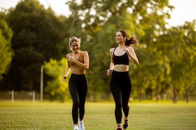 Dwie ładne młode kobiety biegające po parku