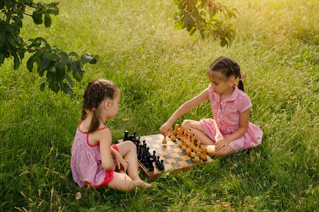 Dwie Małe Dziewczynki Grają W Szachy W Parku W Przyrodzie Pod Drzewem