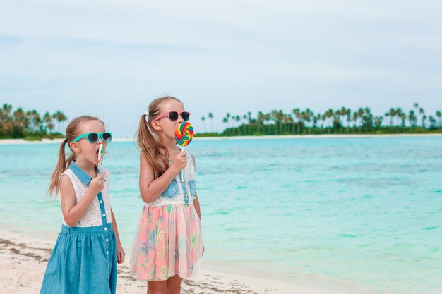 Dwie Małe Dziewczynki Jedzą Jasne Lizaki Na Plaży