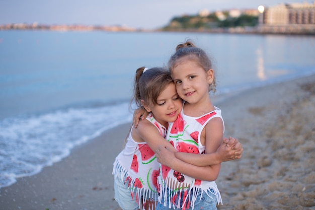 Dwie małe dziewczynki, przytulanie na plaży