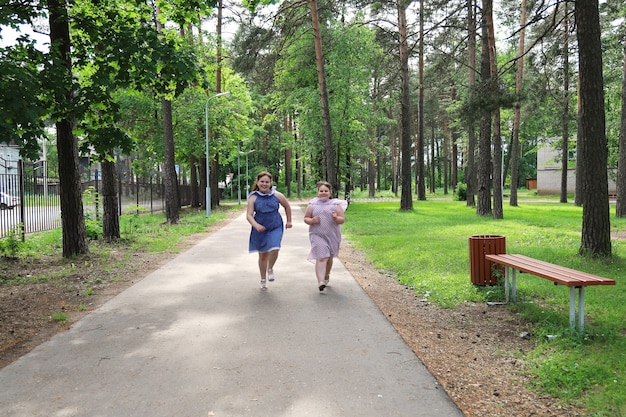 Dwie małe, radosne dziewczynki biegną ścieżką w opuszczonym parku