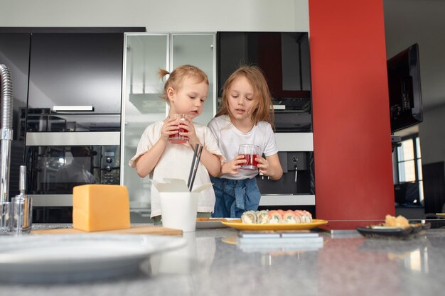 Zdjęcie dwie małe siostry bawiące się i jedzące w kuchni w domu z japońskim jedzeniem