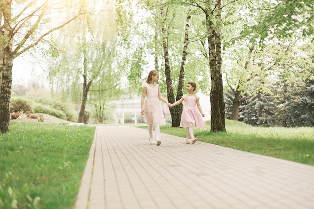Dwie małe siostry spacerujące ścieżką w parku miejskim