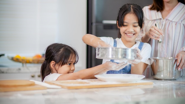 Dwie małe słodkie azjatyckie dziewczynki uczące się robić chleb i piekarnię z ciekawą i szczęśliwą uśmiechniętą twarzą Uczy się i bawi