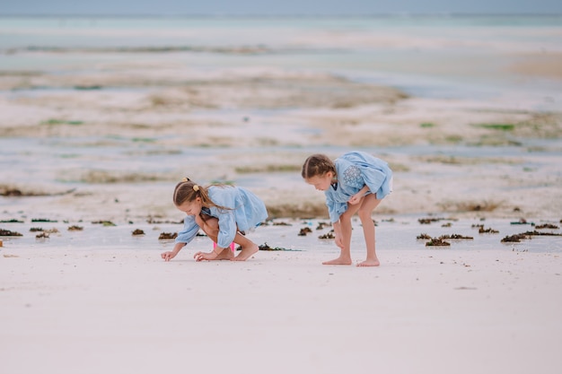 Dwie małe szczęśliwe dziewczynki bawią się razem na tropikalnej plaży