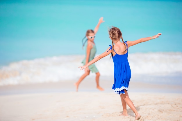 Dwie małe szczęśliwe dziewczyny bawią się razem na tropikalnej plaży