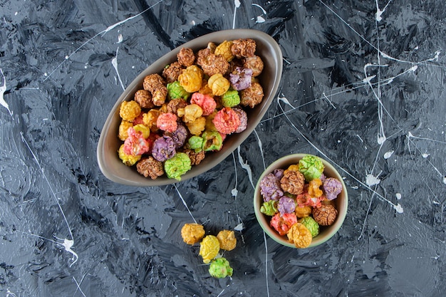 Zdjęcie dwie miski kolorowych smacznych popcornów na marmurowej powierzchni.