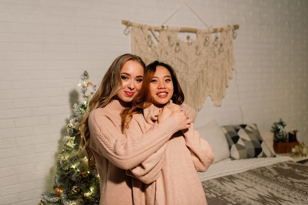 Dwie młode azjatyckie kobiety uśmiechnięte ze szczęścia na przyjęciu bożonarodzeniowym, para lgbt, uroczystość przyjaciół