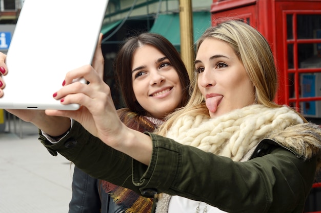 Dwie młode dziewczyny biorąc selfie z tabletem.