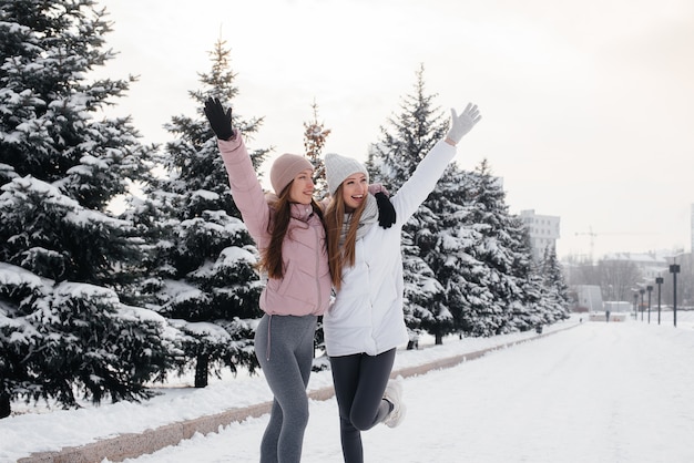 Dwie młode dziewczyny lekkoatletycznego spaceru i uprawiania sportu w słoneczny zimowy dzień. Zdrowy styl życia.