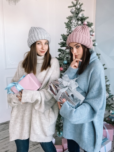 Dwie młode dziewczyny ubieranie się na Boże Narodzenie z prezentami tematu
