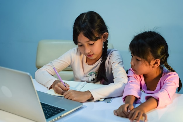 Dwie Młode Dziewczyny Używają Laptopów Do Nauki Online W Domu Podczas Epidemii Koronawirusa (covid-19), Koncepcji Kwarantanny Epidemii.
