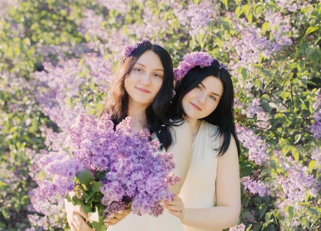 Dwie młode dziewczyny z kwitnącym bzem w słońcu