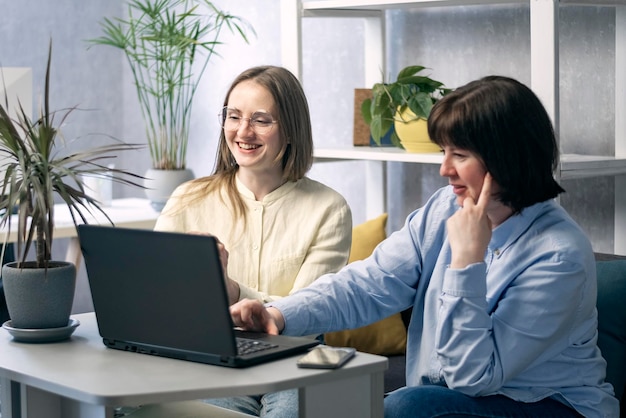 Dwie młode kobiety z laptopem omawiają projekt w miejscu pracy. Partnerzy biznesowi rozmawiają o wspólnej pracy.