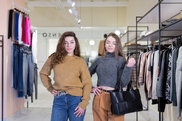 dwie młode koleżanki radują się i robią zakupy w sklepie odzieżowym podczas rabatów