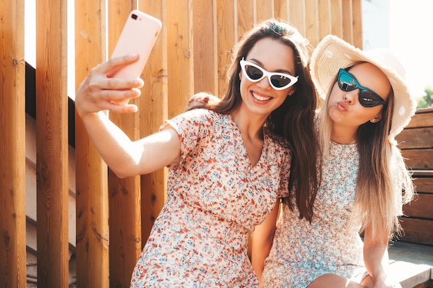 Dwie Młode Piękne Uśmiechnięte Kobiety Hipster W Modnych Letnich Sukienkachseksowne Beztroskie Kobiety Pozują Na Ulicy Pozytywne Czyste Modele Zabawy O Zachodzie Słońca Przytulanie I Szaleństwo