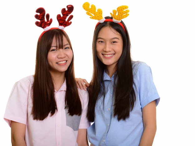 Dwie młode szczęśliwe azjatyckie nastolatki uśmiechnięte gotowe do Bożego Narodzenia