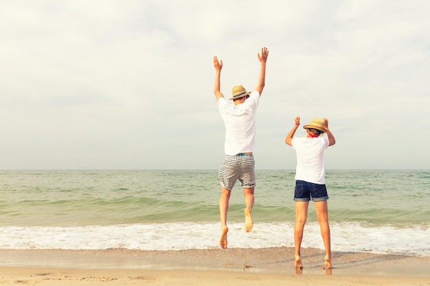Dwie nastolatki, dziewczynka i chłopiec podskakują trzymając się za ręce na plaży nad morzem