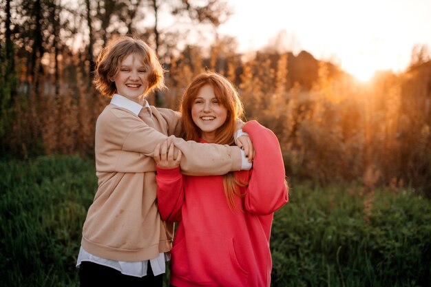 Zdjęcie dwie nastolatki przytulają się o zachodzie słońca i śmieją