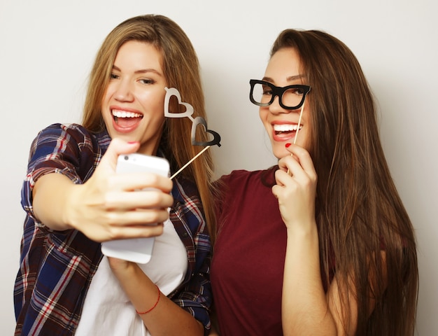 Zdjęcie dwie nastoletnie dziewczyny przyjaciółki w stroju hipster zrobić selfie na telefonie.