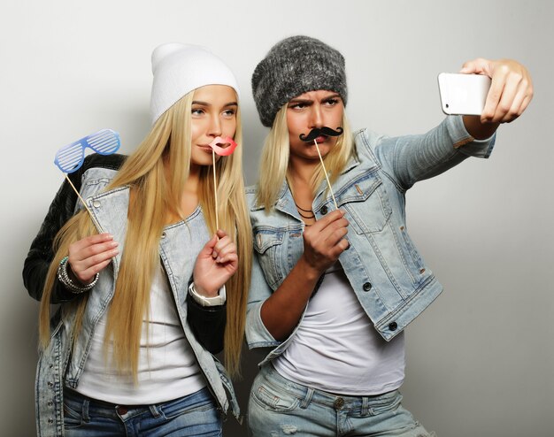 Dwie nastoletnie dziewczyny w stroju hipster zrobić selfie na telefon.