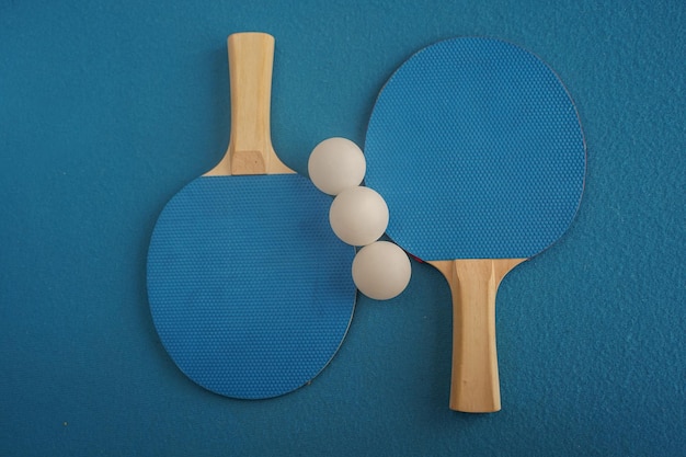 Dwie niebieskie rakiety do tenisa stołowego lub ping-ponga leżą na niebieskim tle z widokiem z bliska Gra rekreacyjna Sprzęt sportowy Międzynarodowe zawody Tenis stołowy Zdrowy styl życia