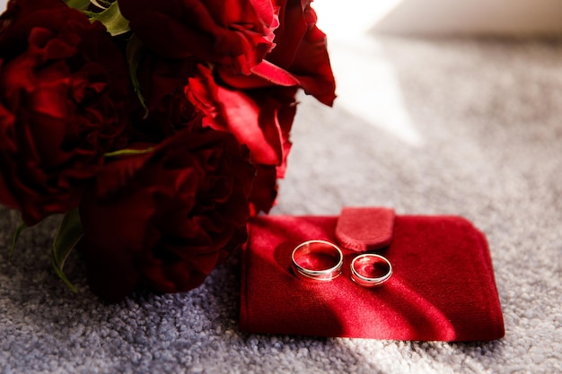 Dwie obrączki z białego i czerwonego złota z bukietem ślubnym z czerwonymi różami