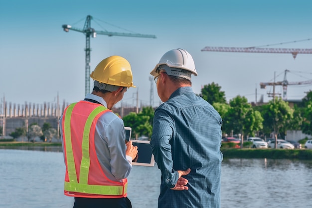 Dwie osoby pracownik Inżynier rozmawia dyskusja przez tablet na miejscu budowy budowy nieruchomości