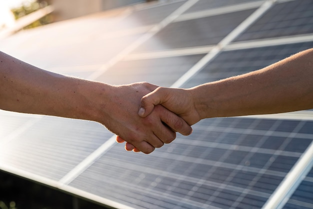 Dwie osoby ściskające dłonie o panel słoneczny po zawarciu umowy w energetyce odnawialnej