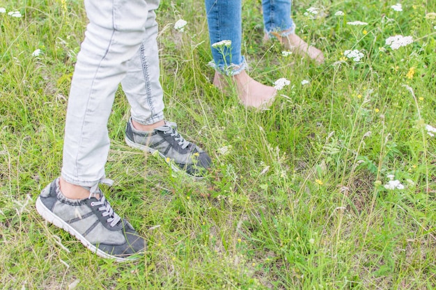 Dwie pary nóg na zielonej trawie W butach i boso w naturze