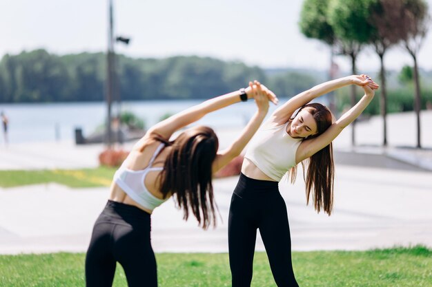 Zdjęcie dwie piękne dziewczyny ćwiczą na świeżym powietrzu w parku