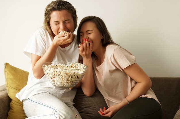 Dwie Piękne Dziewczyny Oglądają Program Telewizyjny I Jedzą Popcorn W Domu
