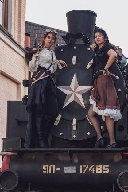 Zdjęcie dwie piękne dziewczyny w steampunkowych ubraniach na tle pociągu