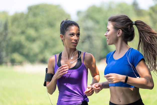 Dwie piękne i atrakcyjne dziewczyny fitness biegają w parku w słoneczny poranek