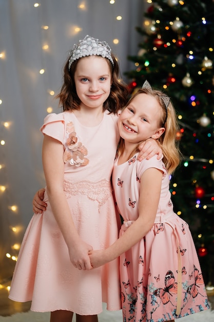 Dwie piękne i szczęśliwe dziewczynki w różowych sukienkach na choince