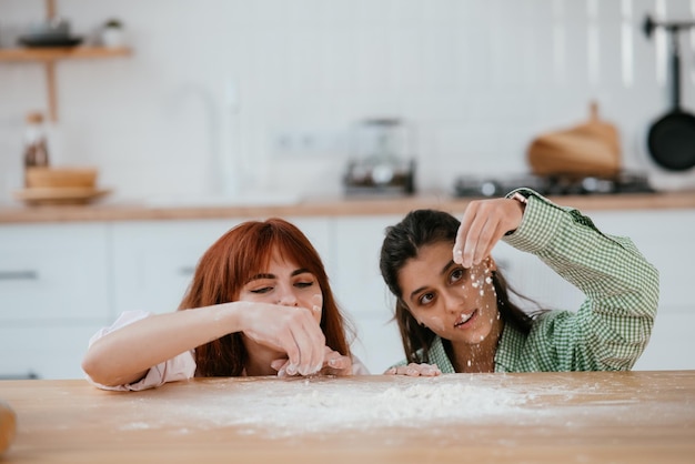 Dwie piękne kobiety bawią się mąką w kuchni