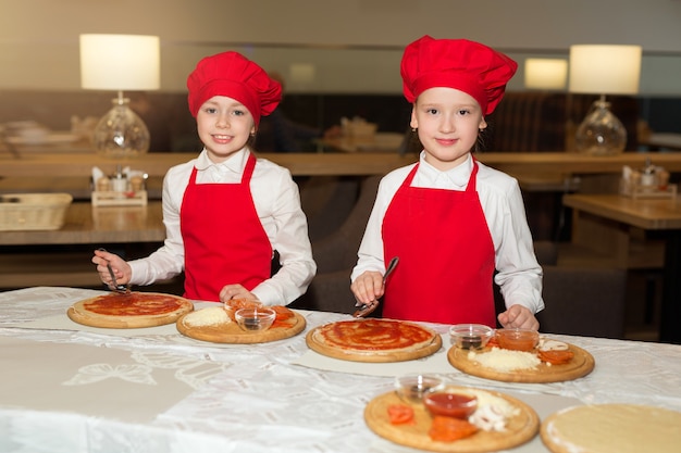 Dwie Piękne Kucharki W Białych Koszulach I Czerwonych Fartuchach W Restauracji Robią Pizzę