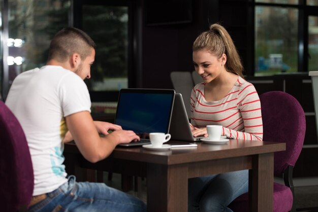 Dwie piękne studentki pijące i bawiące się laptopem w kafeterii