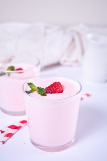 Dwie porcje naturalnego jogurtu domowej roboty w szklanym słoju ze świeżą maliną. Koncepcja śniadania.