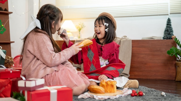 Dwie radosne młode Azjatki lubią jeść świąteczne słodycze świętując Boże Narodzenie w domu