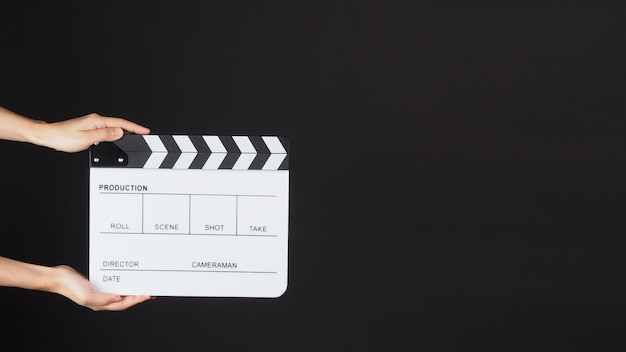 DWIE Ręce trzymają białą clapperboard lub planszówkę filmową. ma zastosowanie w produkcji wideo, filmie, przemyśle kinowym na CZARNYM tle.