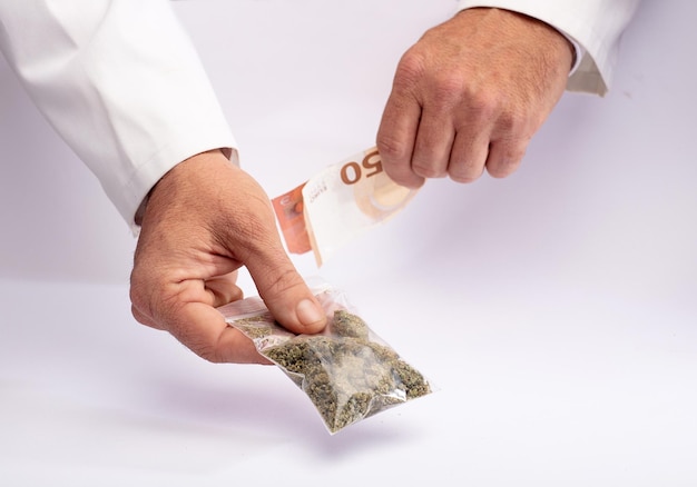 Dwie ręce z marihuaną i pieniędzmi Koncepcja sprzedaży marihuany i narkotyków