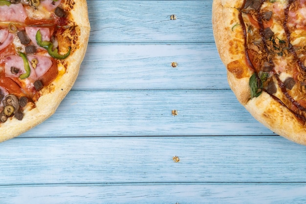 Dwie różne pyszne duże pizze na niebieskim tle drewnianych.