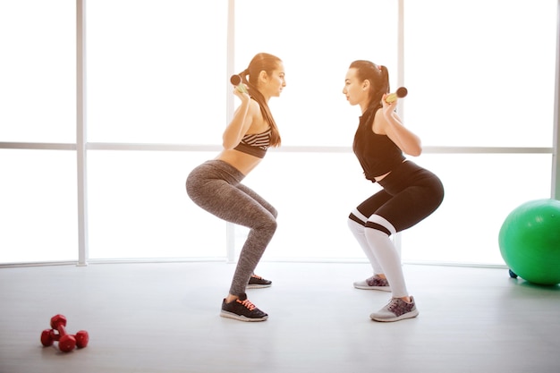 Dwie seksowne młode kobiety robienie treningu w siłowni