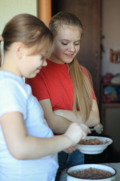 Dwie siostry nastolatki jedzą śniadanie w kuchni, z bliska