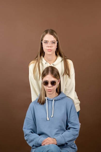 Dwie śliczne blond nastolatka w bluzach i okularach