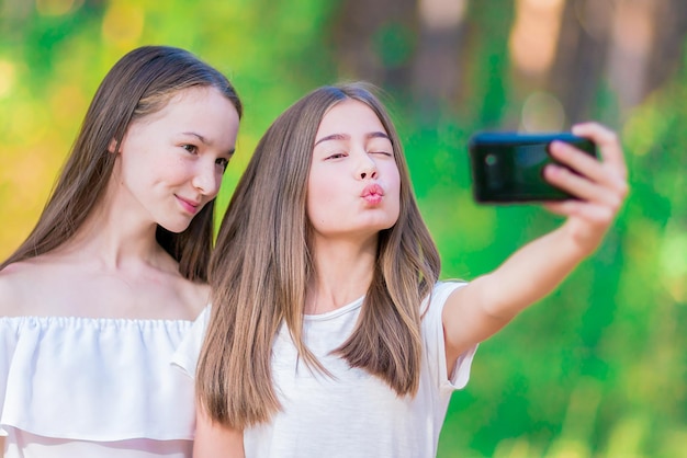 Dwie śliczne dziewczyny robią sobie selfie w letnim lesie