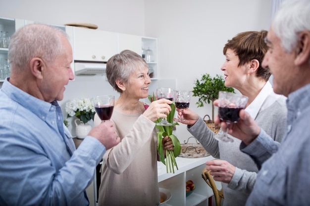 Dwie starsze pary świętują, wznosząc toast czerwonym winem