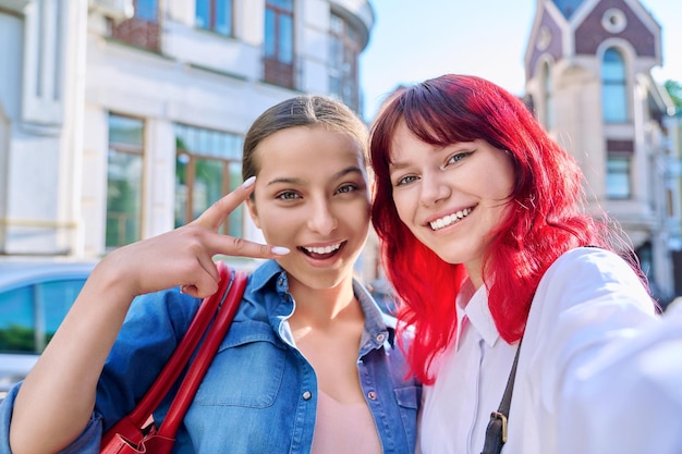 Dwie szczęśliwe nastoletnie kobiety biorące razem portret selfie na ulicy miasta