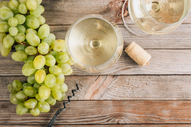 Dwie szklanki białego wina i winogron na vintage drewnianym stole